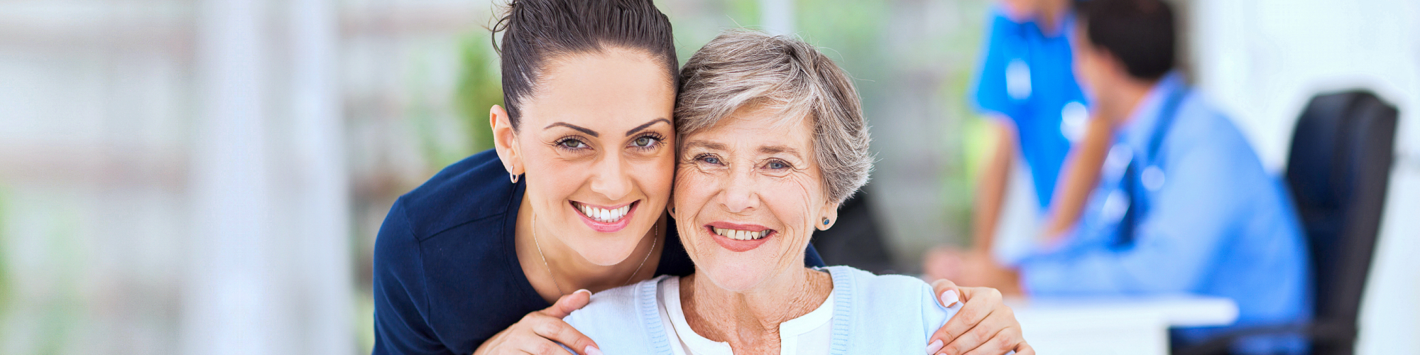 caregiver hugging senior woman while smiling